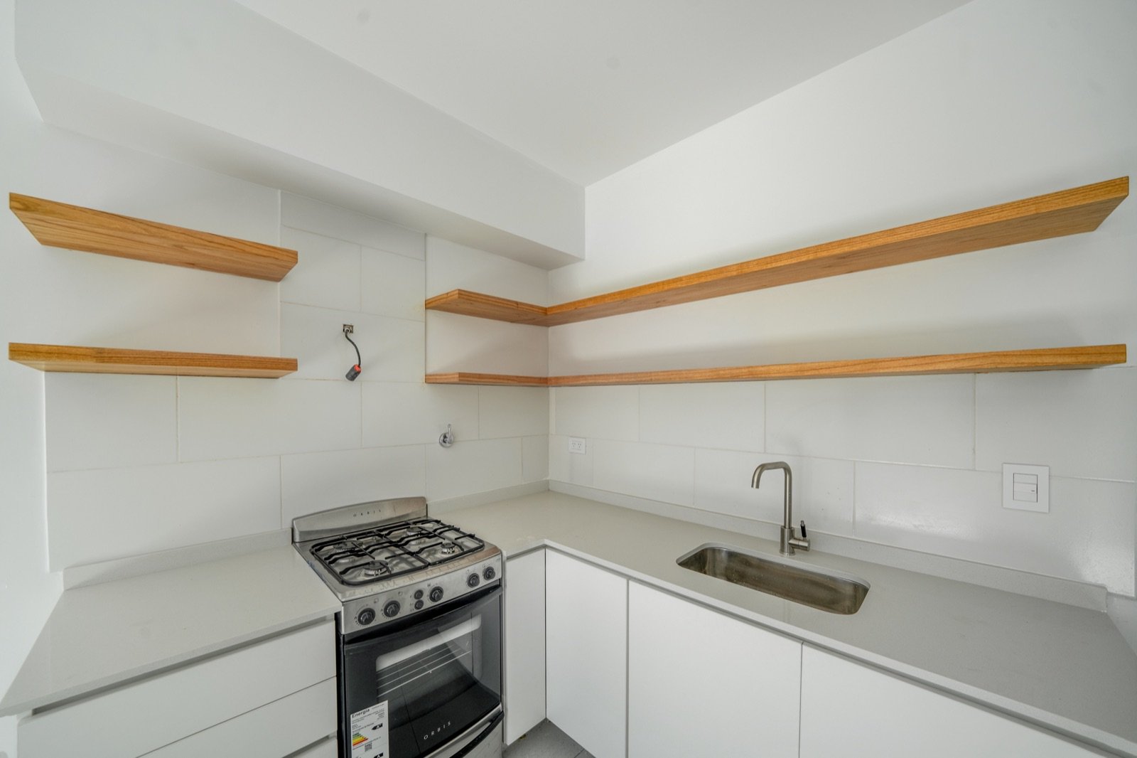 Cocina con mesada blanca y estantes de madera